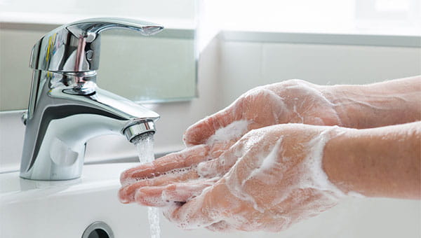 A man washing his hands with soap and water at a bathroom sink