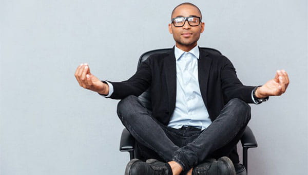 A person seated cross-legged in an office chair meditating
