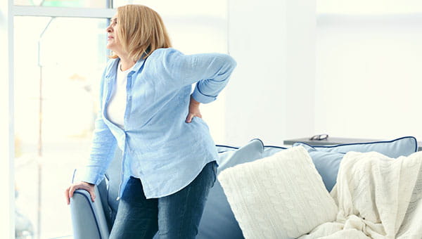 A woman standing up while grabbing her back