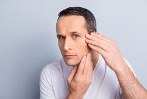 man examining his face in a mirror