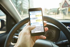 someone driving a car while texting on a cell phone