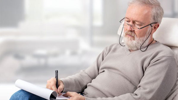 A senior man is taking notes as he studies his Medicare options.