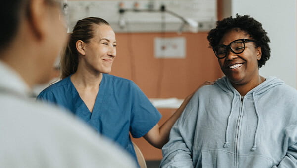 A nurse puts her hand on a patient's shoulder.