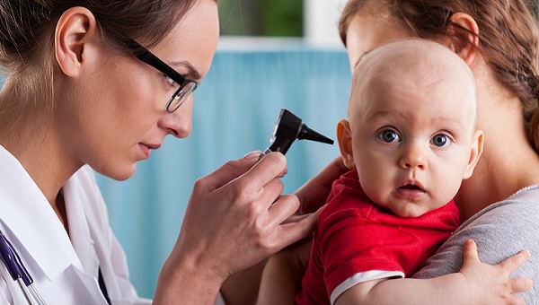 A pediatrician is checking a baby's ears.
