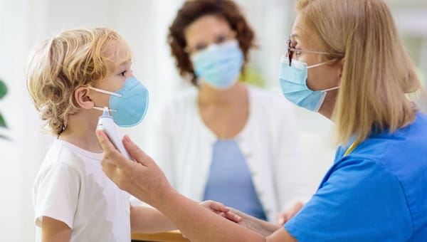 A mother is watching her child being examined by his health care provider during an office visit.