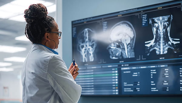 a female scientist in a lab coat examines screens of x rays