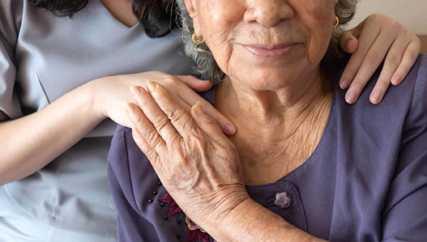 a caring woman supports an elderly womans arm