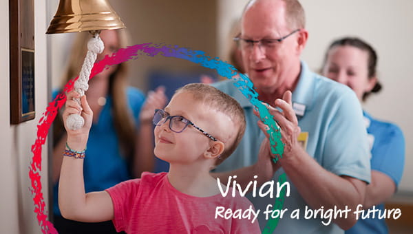 A child around 6 years old smiling and ringing a victory bell, with health care providers clapping and cheering in the background. The photo has words that say, Vivian, ready for a bright future.