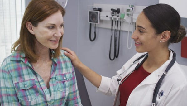 A female doctor smiles at a female patient. 