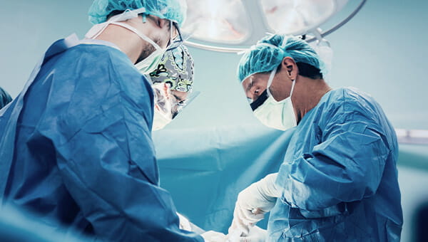 Two surgeons in the middle of performing surgery on an unseen patient.