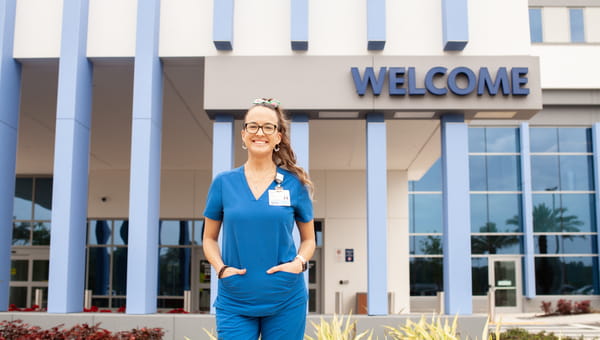 Already Applied or Current Team Member? Female BayCare team member smiling outside of a BayCare facility.