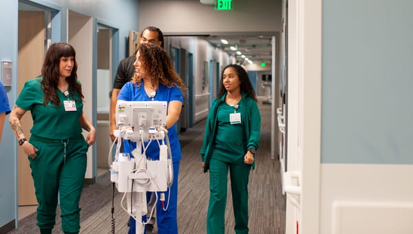 Group of BayCare team members walking down a hall with a piece of medical equipment.