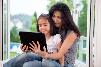 A woman and her daughter use a tablet for an online doctor visit.