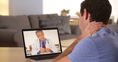 man holding his neck while having a virtual doctor's visit
