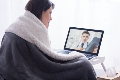 woman in a bathrobe having a virtual doctor's visit