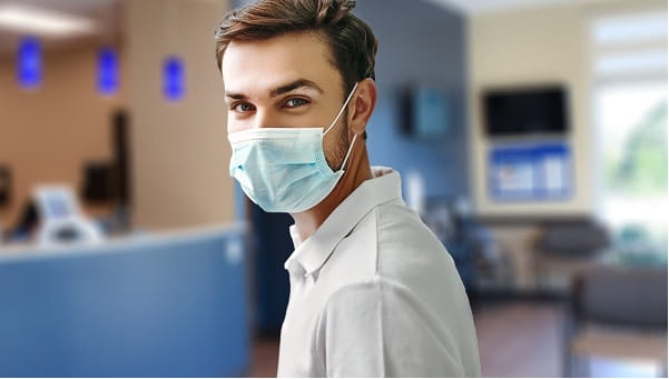 young male wearing a mask standing in an urgent care center