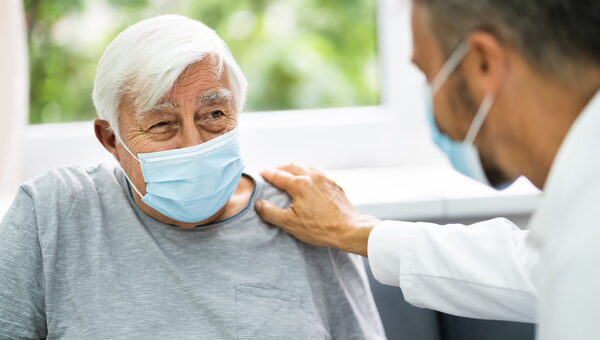 Male physician speaking with male patient wearing a mask