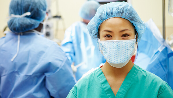 Medical provider wearing a face mask and hair net in an operating room