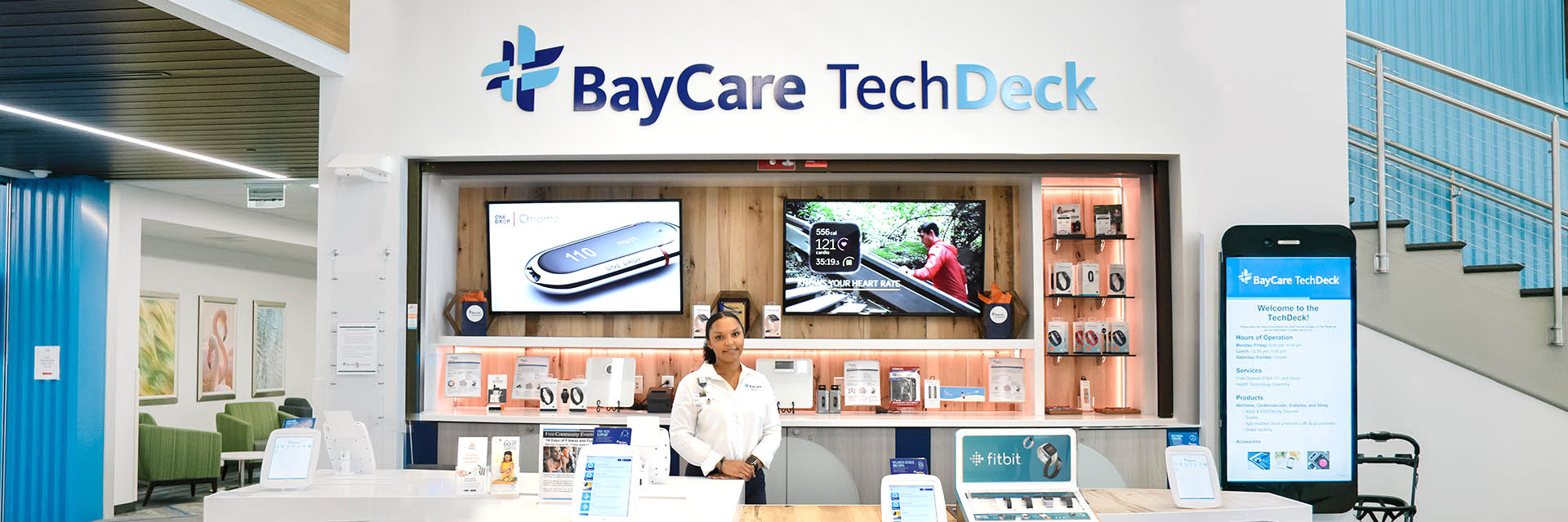 A BayCare employee standing in front of a BayCare TechDeck station.
