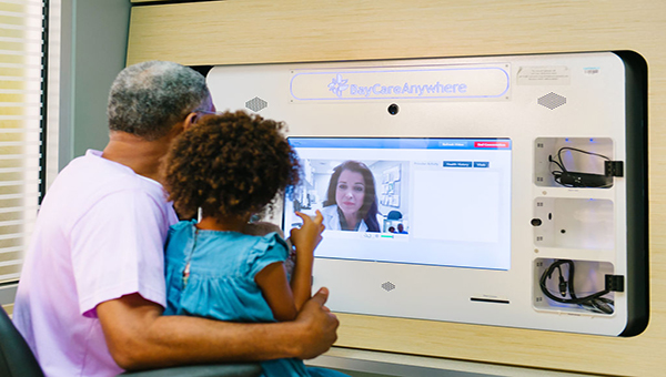 adult with child having a virtual visit at a walkin care kiosk