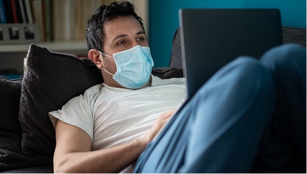 Adult male wearing a mask and working on a laptop