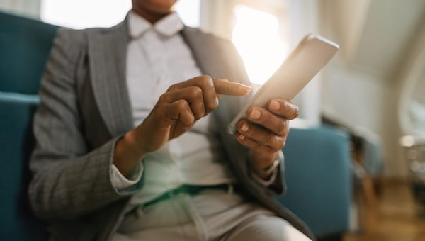 Closeup of black businesswoman text messaging on cell phone while working at home