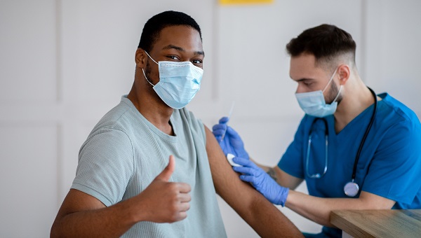 A man is wearing a mask and getting vaccinated.