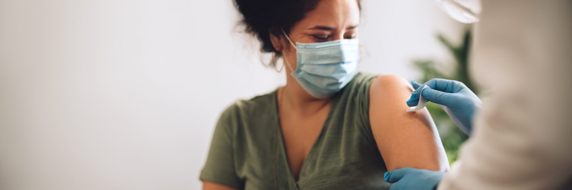 A woman is wearing a mask and getting vaccinated.