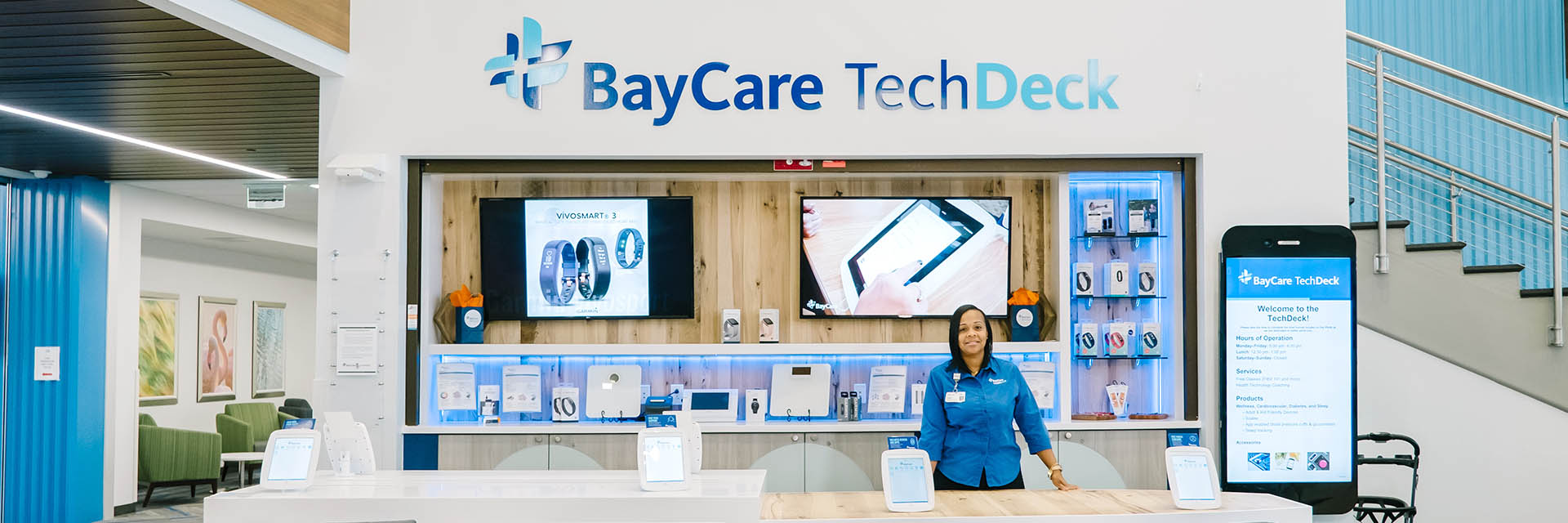 A team member is standing in front of the BayCare TechDeck at a BayCare HealthHub.