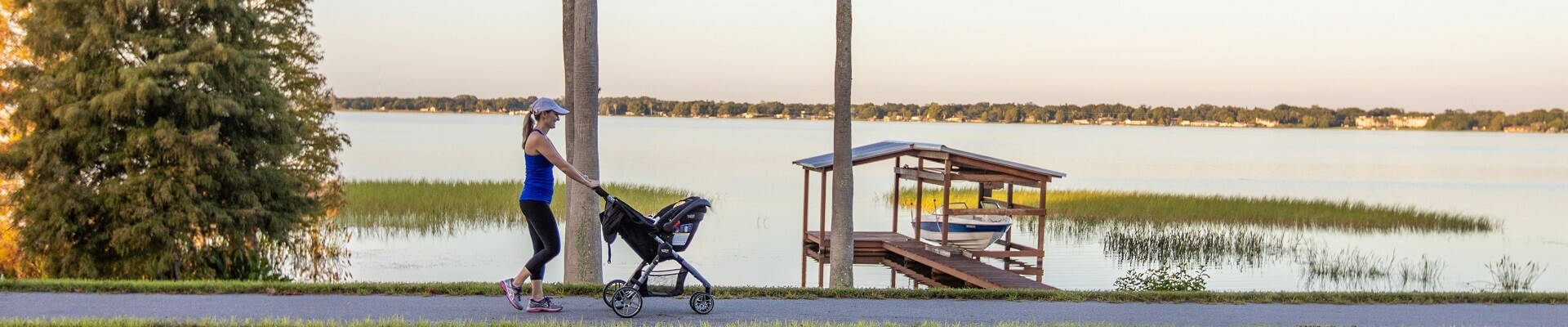 A woman is walking around a Winter Haven, Florida lake while pushing her baby's stroller.
