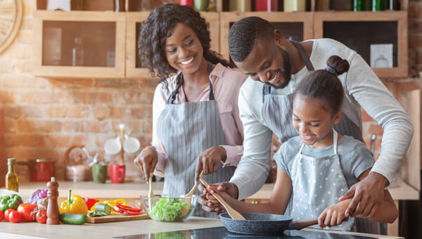 a mother father and son cooking together in the kitchen with ingredients on the table