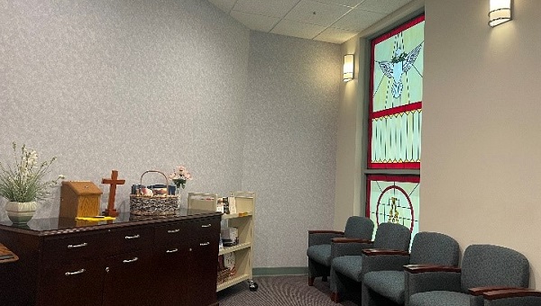 a room with a several chairs a window and cross at bartow medical center