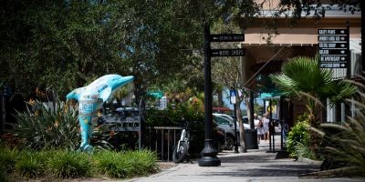 Picturesque downtown area of Dunedin, Florida with shops and a dolphin statue.