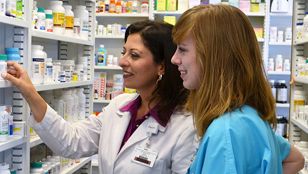 A pharmacist talks with a team member in the pharmacy