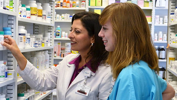 A pharmacist talks with a team member in the pharmacy