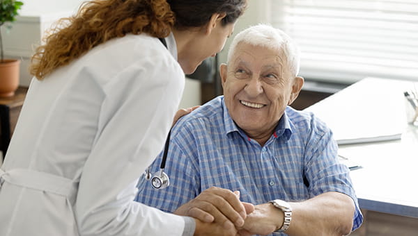 A doctor talking to an elderly patient while holding each others hands