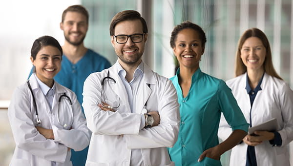 Five doctors standing together and smiling at the camera