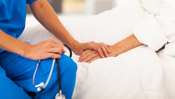 A nurse is holding a patient's hand.