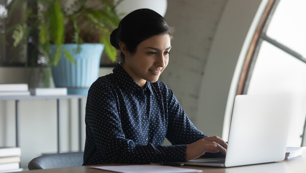 Confident Indian businesswoman entrepreneur working on laptop in modern office