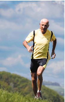A senior citizen man jogging on a hill