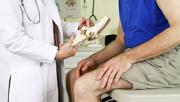 doctor giving instructions to a patient holding their knee