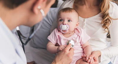 A doctor is checking the heartbeat of a baby during a visit.