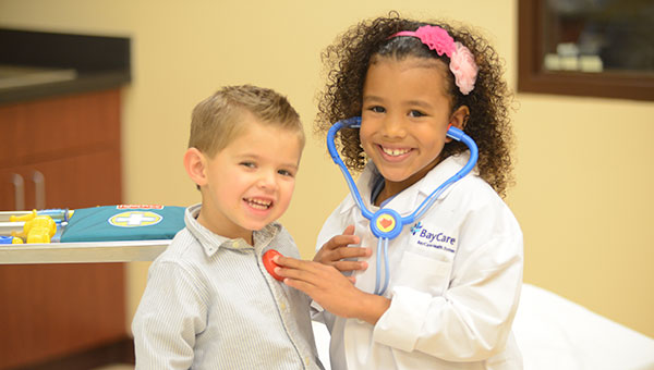 Girl pretending to examine young boy