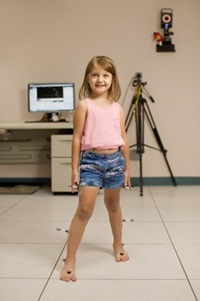 Girl in pink shirt and shorts participating in a motion analysis