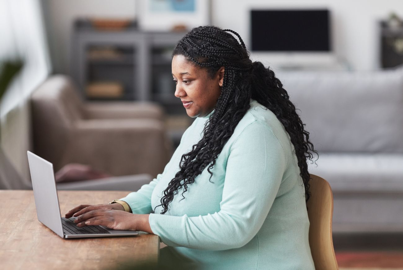 Side view portrait of curvy African American woman using laptop at desk