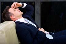man in a business suit sitting on a couch leaning his head back