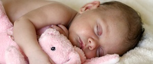 Sleeping baby holding pink bunny