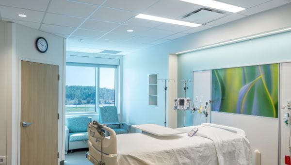 hospital room with made bed with open window view of trees