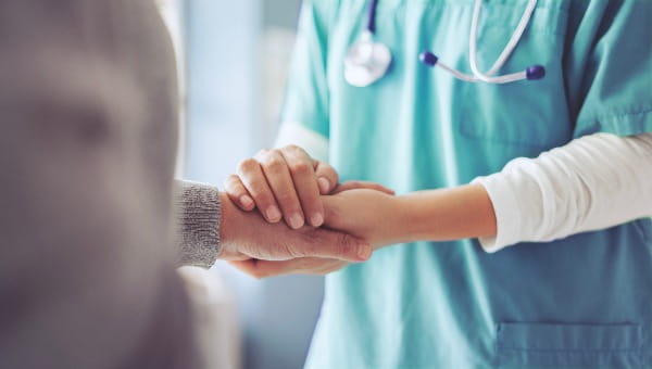 A physician is holding the hand of a patient.