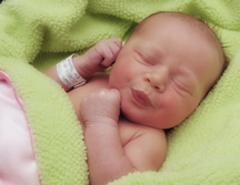 infant with hospital bracelet wrapped in bright green blanket